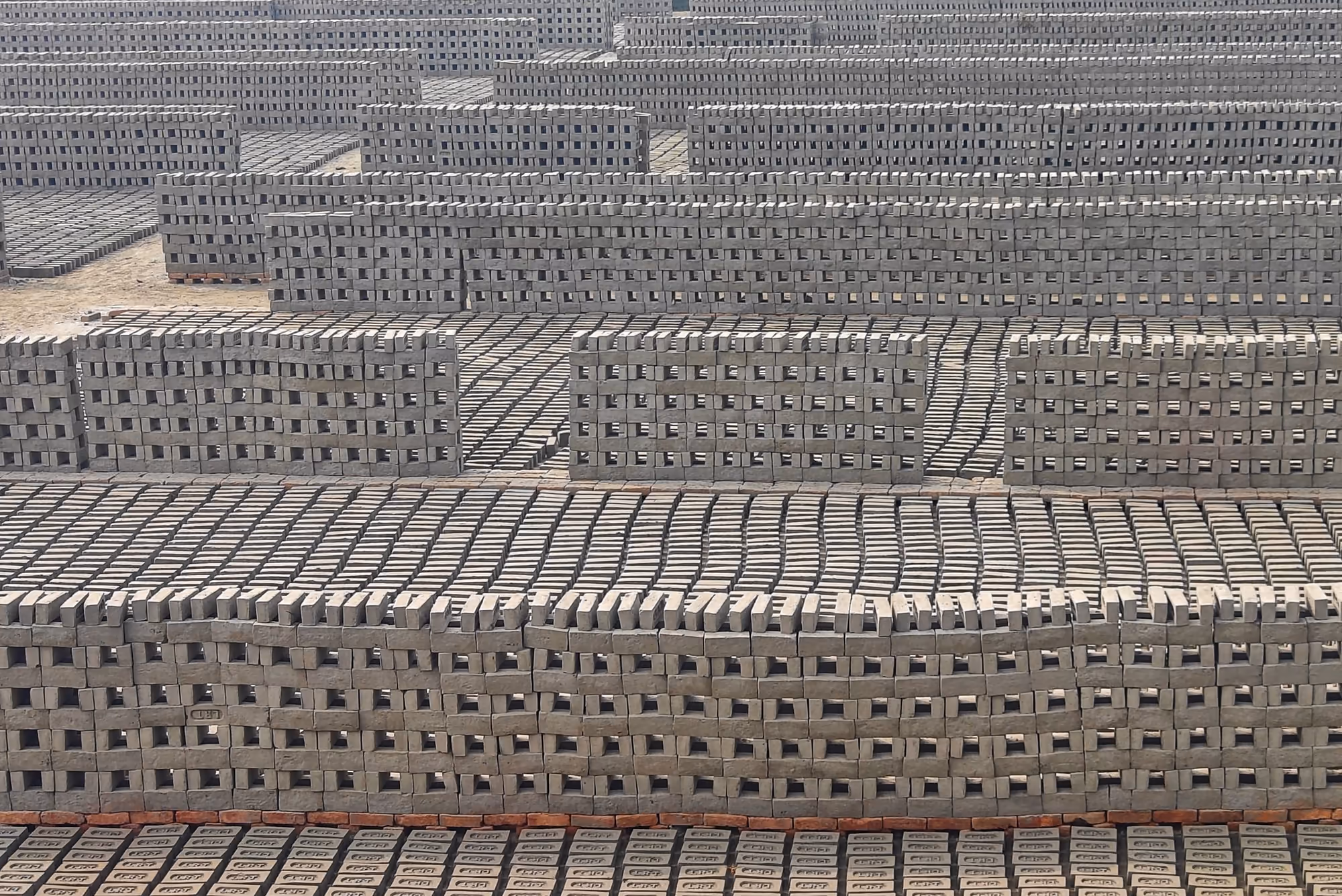 Rangées d'agglos en béton qui sèchent à l'air libre avant d'être palettisés