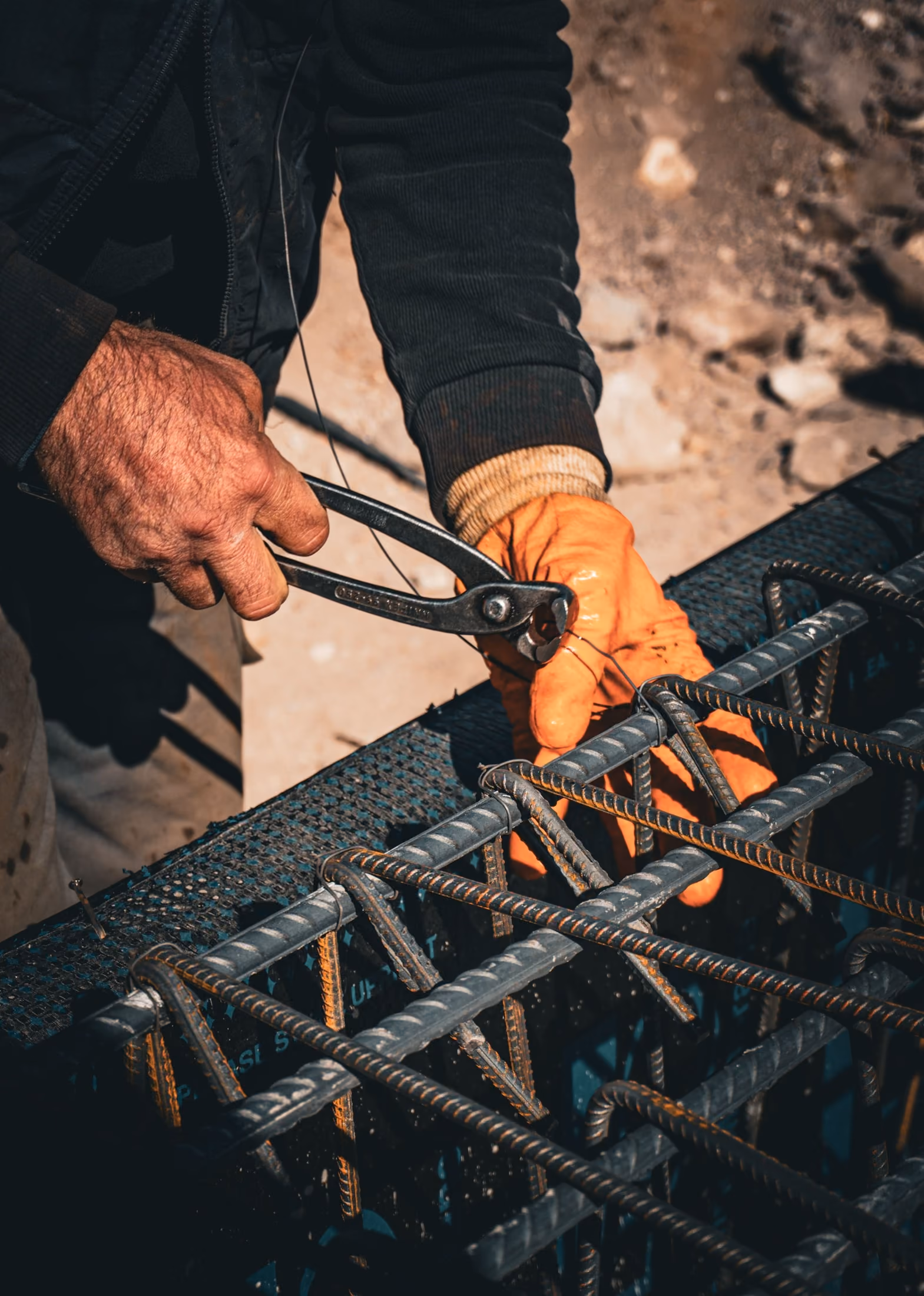 Mains gantées ligaturant des armatures en acier avant le coulage du béton